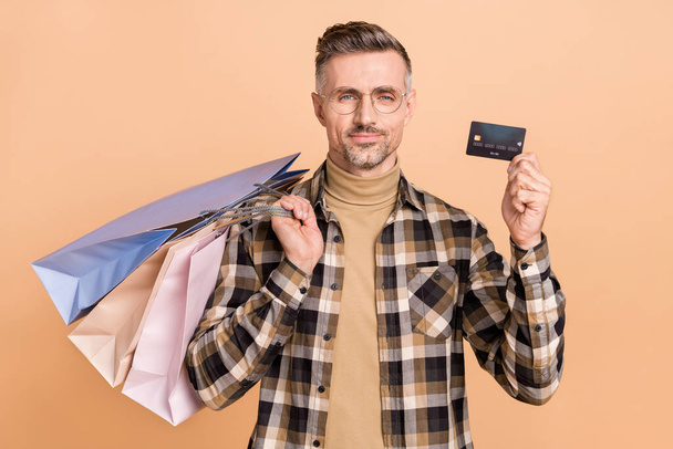 Photo of mature man glad hold package bargain debit card transaction salary mall isolated over beige color background - Photo, Image