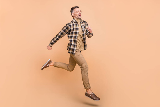 Full body profile side photo of cheerful man run look empty space motion rush isolated over beige color background - Foto, Imagem