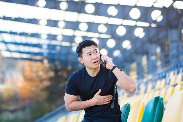 Corredor asiático masculino tiene dolor torácico severo, dolor de corazón después de correr y entrenar, llamar a una ambulancia llama a un médico rápidamente - Foto, Imagen