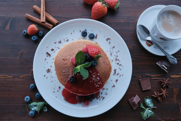 Plate of fresh pancakes piled with fresh fruit and covered in syrup/ Daylight shot - Valokuva, kuva