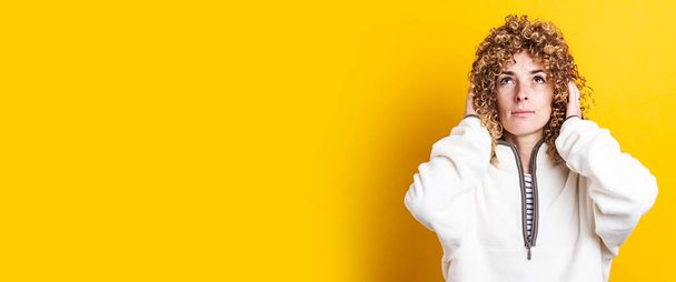 Nuori nainen, jolla on kihara afrikkalainen tukka, katsoo keltaista taustaa. Banneri - Valokuva, kuva
