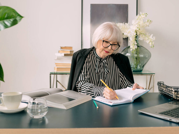 senior beautiful gray hair woman  drinking water during work in office. Work, senior people, water balance, find a solution, experience concept - Foto, Imagem