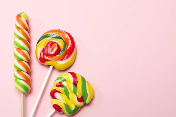 Sweet lollipops on pink background, flat lay. Space for text - Zdjęcie, obraz