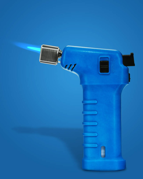 A gas blow torch kitchen with blue flame on the blue background. - Photo, Image