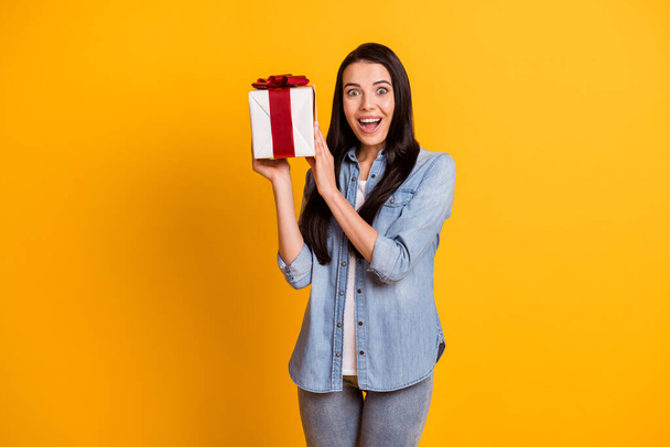 Portrait of astonished cheerful person arms hold little giftbox open mouth isolated on yellow color background - Foto, afbeelding