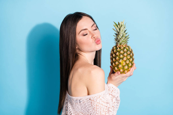 Profile side photo of charming stunning young woman hold pineapple send air kiss isolated on blue color background - 写真・画像