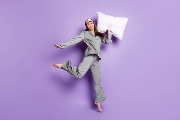 Full length body size view of lovely trendy glad cheery girl holding pillow jumping having fun isolated on violet purple color background - Foto, immagini
