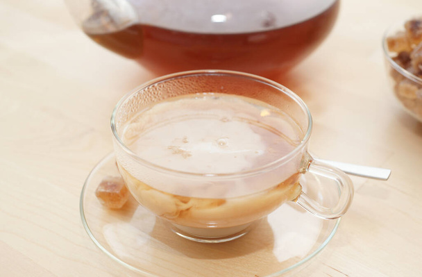 Черный чай в стакане с молоком в кастрюле и сахарной пудрой  - Фото, изображение