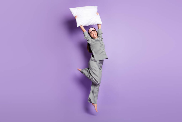 Pełna długość ciała rozmiar zdjęcie dziewczyny skacząc z białą poduszką na piżamie partii odizolowane pastelowy fioletowy kolor tła - Zdjęcie, obraz
