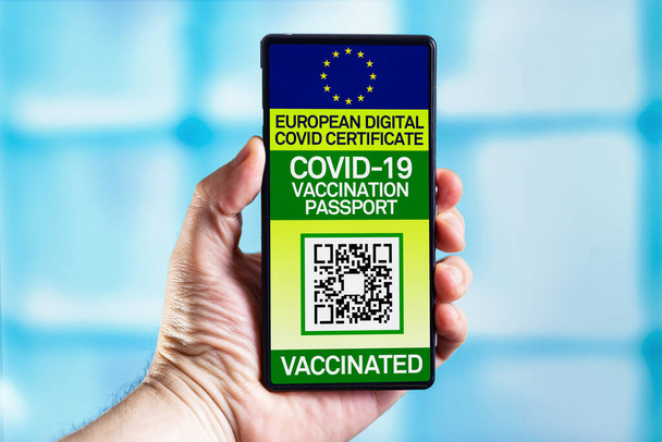 Ο ταξιδιώτης παρουσιάζει ευρωπαϊκό διαβατήριο υγείας με πιστοποίηση εμβολιασμού κατά της νόσου του Coronavirus. Smartphone ενός τουρίστα που δείχνει ασυλία ψηφιακό διαβατήριο που πιστοποιεί τον εμβολιασμό τους κατά του ιού COVID-19 - Φωτογραφία, εικόνα