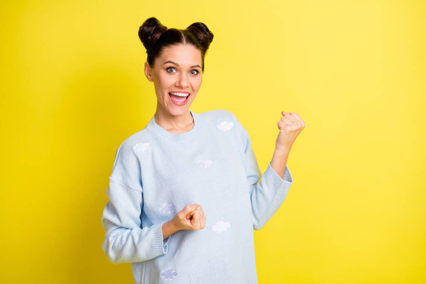 Photo of young beautiful attractive smiling cheerful excited girl hold fists in victory isolated on yellow color background - 写真・画像