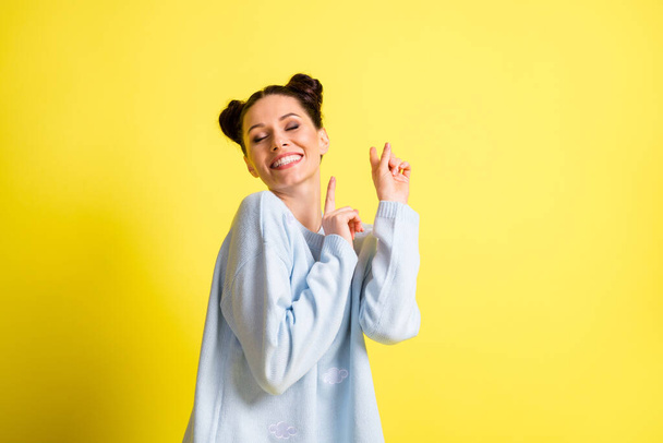 Photo of dreamy lady closed eyes raise fingers toothy beaming smile wear blue pullover isolated yellow background - Valokuva, kuva