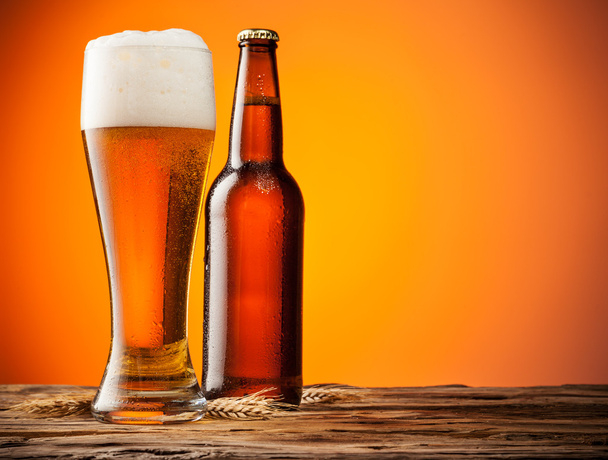 γυαλί και μπουκάλι μπύρα με πορτοκαλί φόντο - Φωτογραφία, εικόνα