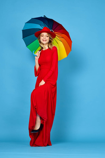 woman in red dress multicolored umbrella blue background - Фото, зображення