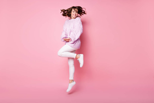 Volledige lengte lichaam grootte uitzicht van mooie verlegen vrolijke golvende haren meisje springen plezier poseren geïsoleerd op roze pastel kleur achtergrond - Foto, afbeelding