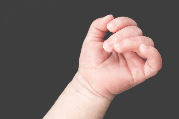 A closeup shot of a baby's hand on a gray background - Foto, Imagem
