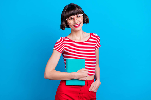 Photo portrait girl in glasses smiing keeping book preparing for exam isolated bright blue color background - Φωτογραφία, εικόνα