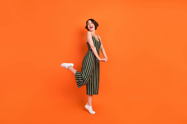 Full length profile side photo of young excited girl happy positive smile look empty space isolated over orange color background - Fotó, kép