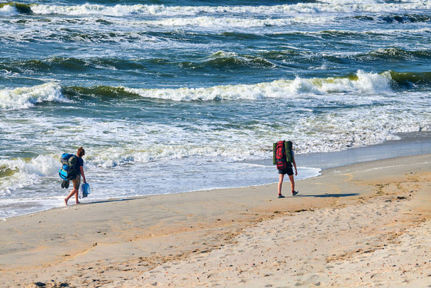Две молодые женщины-туристы путешествуют по морю. Девушки путешественники с большими рюкзаками исследуют новый маршрут, красивый фон Балтийского моря. Путешествие для женщин - Фото, изображение