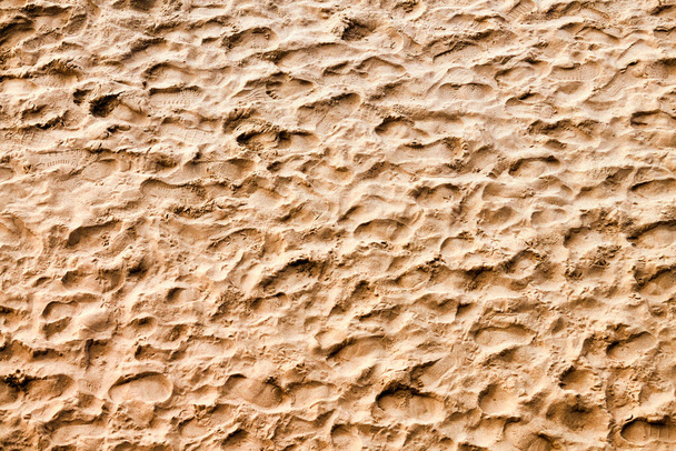 Следы на песке, вид сверху на пляж. Песчаный пляж с золотым песком и множеством следов людей. Летний текстурный фон - Фото, изображение