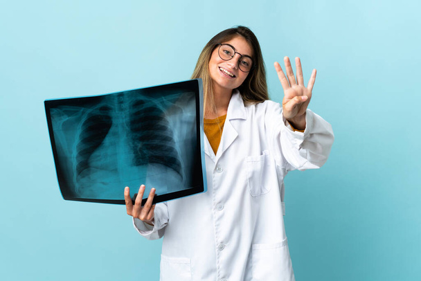 Professional traumatologist isolated on blue background happy and counting four with fingers - Photo, Image