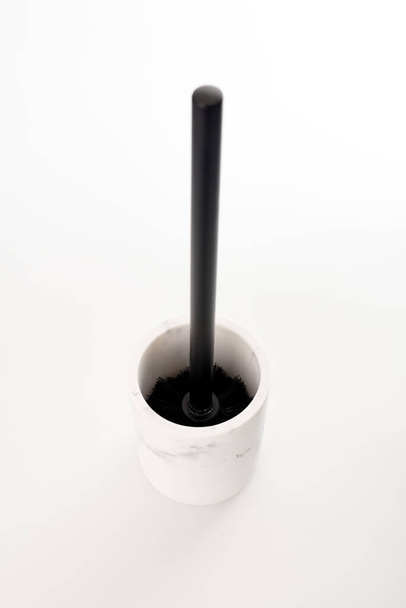 Escova de banheiro preto no moderno suporte de pedra branca isolado fundo branco. Ferramenta de WC para limpeza vaso sanitário. Escova para limpador de toalete e superfície do vaso sanitário alvejante - Foto, Imagem