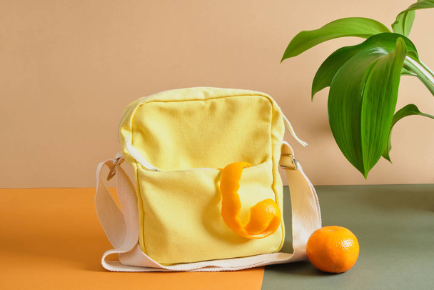 a bag made of waste fruits, cloth made of leaves and unusable food, yellow cloth bag and orange peel on a green background - Foto, Imagen