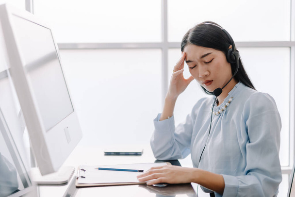 Call center operators provide advice and counseling to help clients with stressful gestures, operators are having a headache and use their hands to touch their heads with a tired expression. - Foto, afbeelding