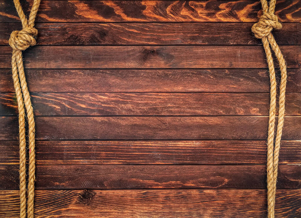 Wooden background made of dark brown boards with hemp ropes. Deck texture. - 写真・画像