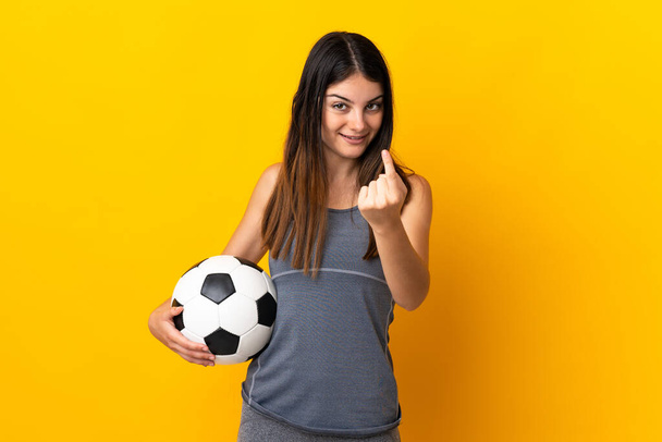 Jovem jogador de futebol mulher isolada no fundo amarelo fazendo gesto vindo
 - Foto, Imagem