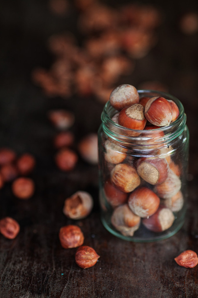 Hazelnuts in a glass jar cup on a dark table - Valokuva, kuva