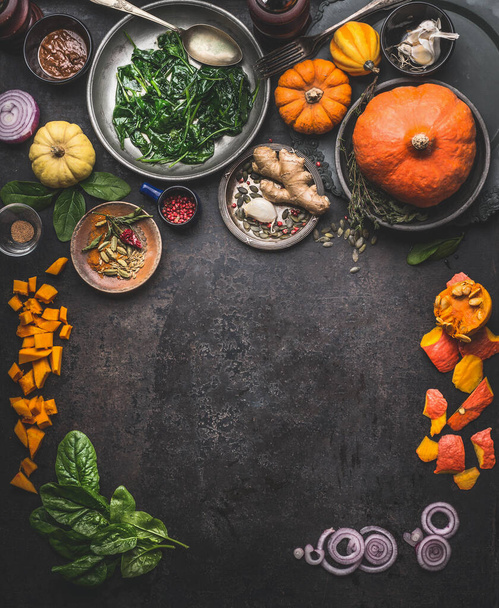 Vegetarian seasonal food background with ingredients for herbs and winter cooking: pumpkin,spinach, ginger, onion. Top view. Frame. Copy space - Foto, Bild