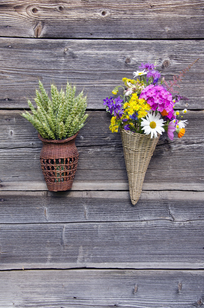 deux paniers en osier avec des fleurs et des épis de blé sur le mur
 - Photo, image