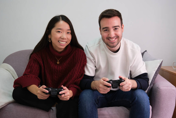 Jeune couple multiracial s'amusant à jouer à des jeux vidéo. - Photo, image
