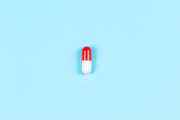 Una cápsula de píldora de medicina colorida sobre fondo azul claro. Vista superior, plano, espacio de copia para texto - Foto, imagen