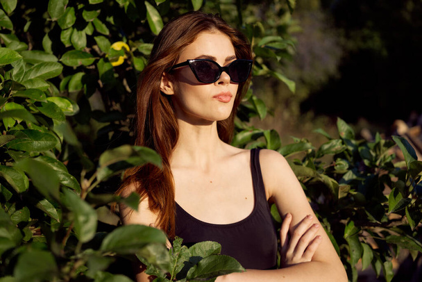 pretty woman in sunglasses in summer outdoors green leaves - Foto, Imagem