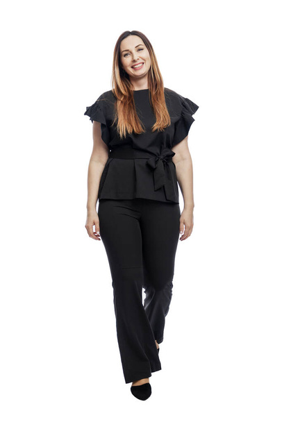 Laughing woman in a suit walks. Beautiful brunette in black trousers and a blouse. Business success. Isolated on white background. Vertical. Full height. - Φωτογραφία, εικόνα