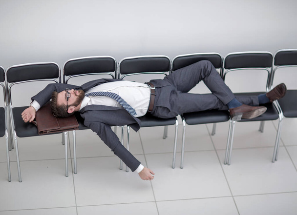 young businessman sleeping on chairs in the office hallway - Foto, Imagem