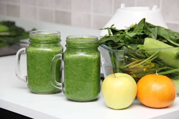 Jugo verde servido en un frasco de albañil con verduras como pepino, acelga, espinacas, limón y frutas para un desayuno saludable y nutritivo. - Foto, imagen