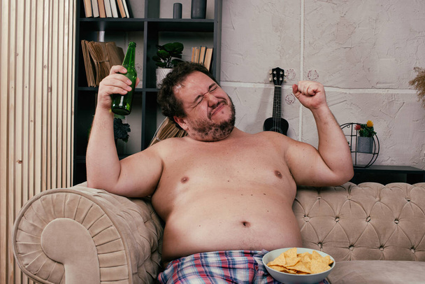 Funny fat man drinking beer at home. - Photo, Image