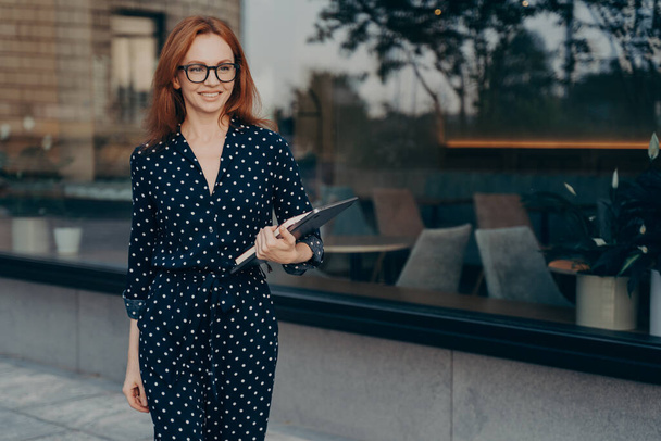 Enthousiaste femme d'affaires prospère en tenue élégante tient tablette et journal - Photo, image