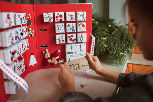 Kaunis tyttö omistaa alkuperäisen adventti kalenteri valmistettu koruja laatikot ja sideaine, Joulu diy veneet - Valokuva, kuva
