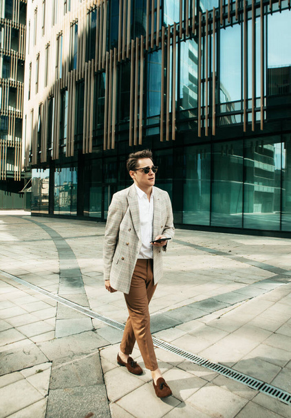 Geschäft, Menschen und Erfolgskonzept: Schöner junger Mann in schickem Outfit spaziert durch modernes Büro - Foto, Bild