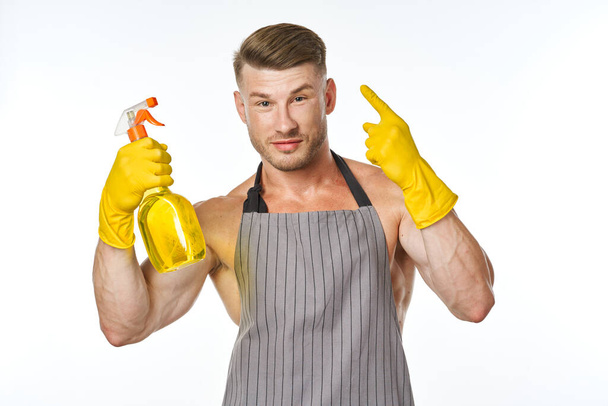 pumped up man in an apron with rubber gloves detergents - Foto, immagini