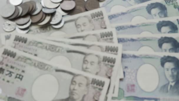 Japanin jenin rahakonsepti. lähikuva Japanin jenistä puupöydällä.Jen on Japanin valuutta, jota käytetään muuttumaan, ostamaan, myymään, keräämään ja investoimaan japanilaisiin.. - Materiaali, video