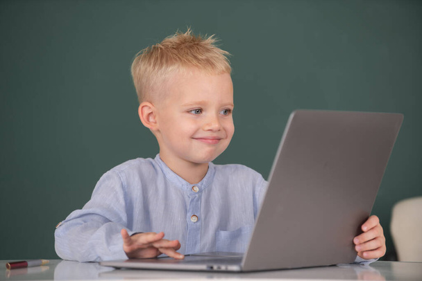 Portrait of attractive cheerful boy using laptop. Little funny programmer. - Zdjęcie, obraz