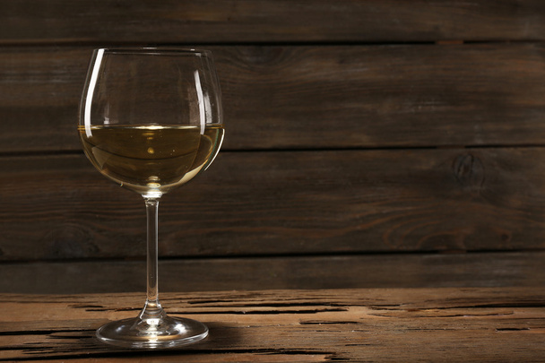 Goblet of white wine on wooden table on wooden wall background - Foto, afbeelding