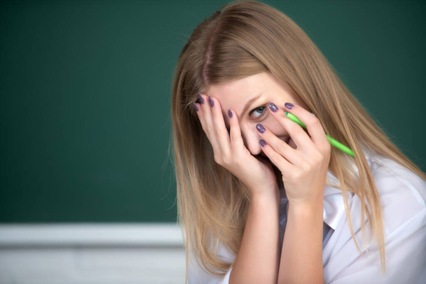 Portrait of a young shame embarrassed female student studying in school classroom. - Foto, imagen
