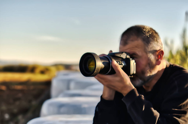 Человек в черном с камерой, фотографирующий на закате - Фото, изображение