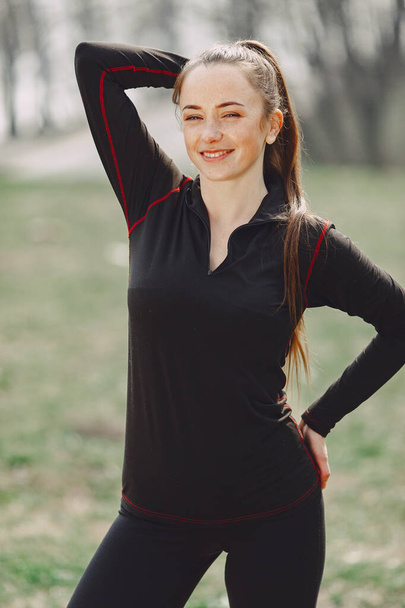Elegant woman in a black uniform in a spring park - Fotoğraf, Görsel